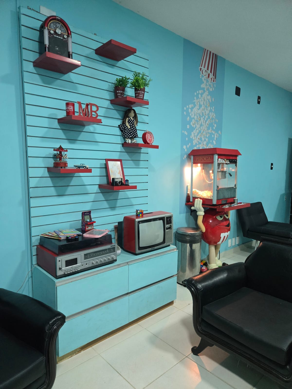 Parede temática com TV antiga, vitrola e a famosa máquina de pipoca